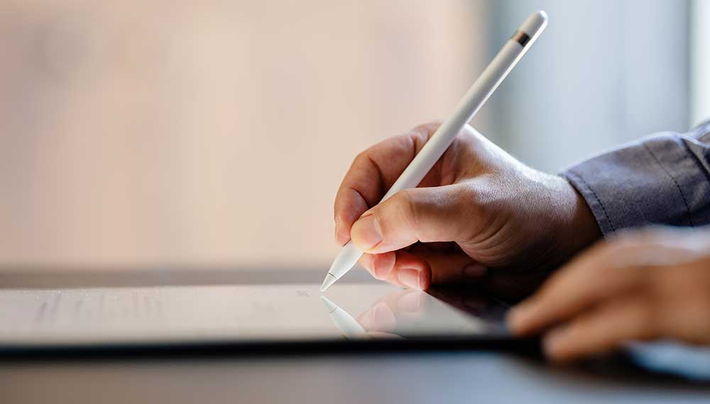 person writing with stylus on ipad
