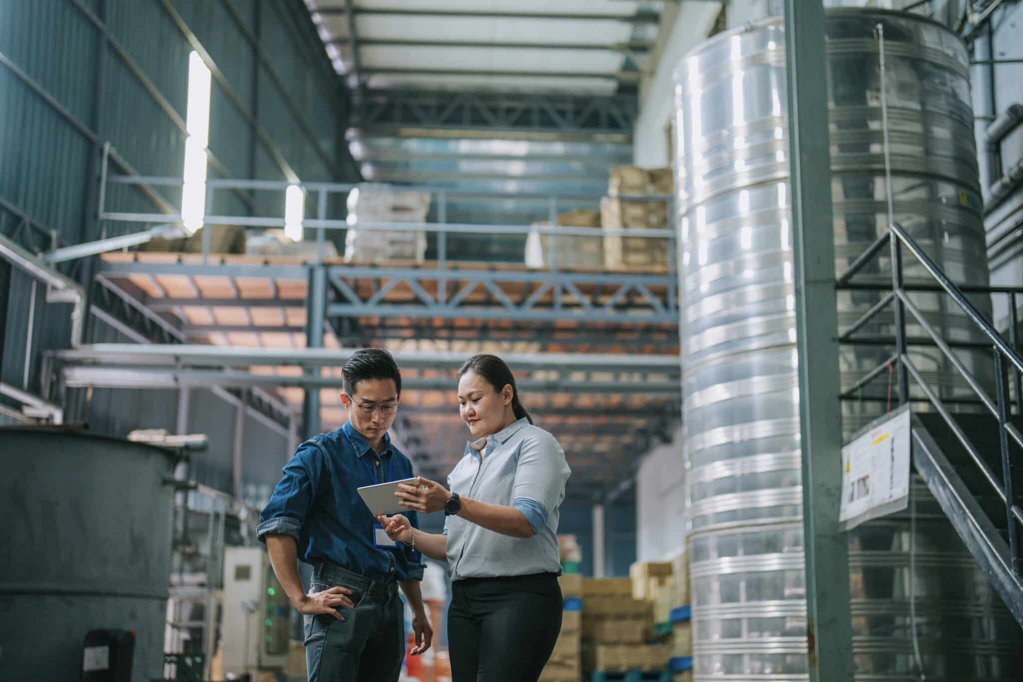 Asian female manager talking to warehouse foreperson worker in factory