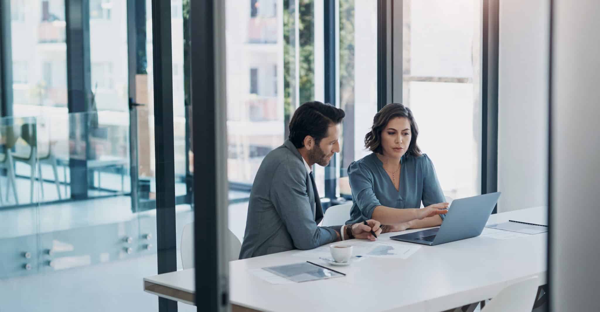 Business man, woman and laptop in discussion for deal, agreement and proposal for b2b collaboration. People, computer and meeting with paperwork for financial strategy, stats or negotiation in office